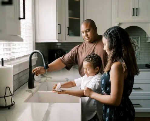 Family in kitchen washing hands using propane heated water