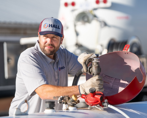 Propane delivery specialist filling a tank