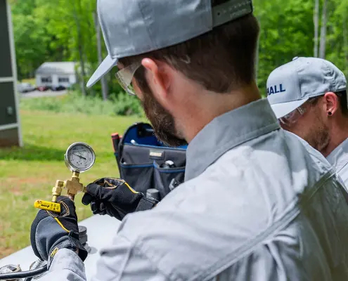 Hall technician checking a pressure gauge on a propane tank
