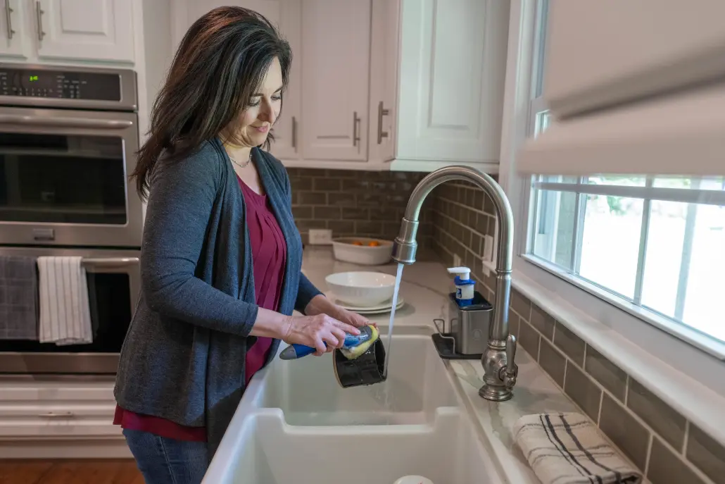 Person washing dishes in a kitchen sink
