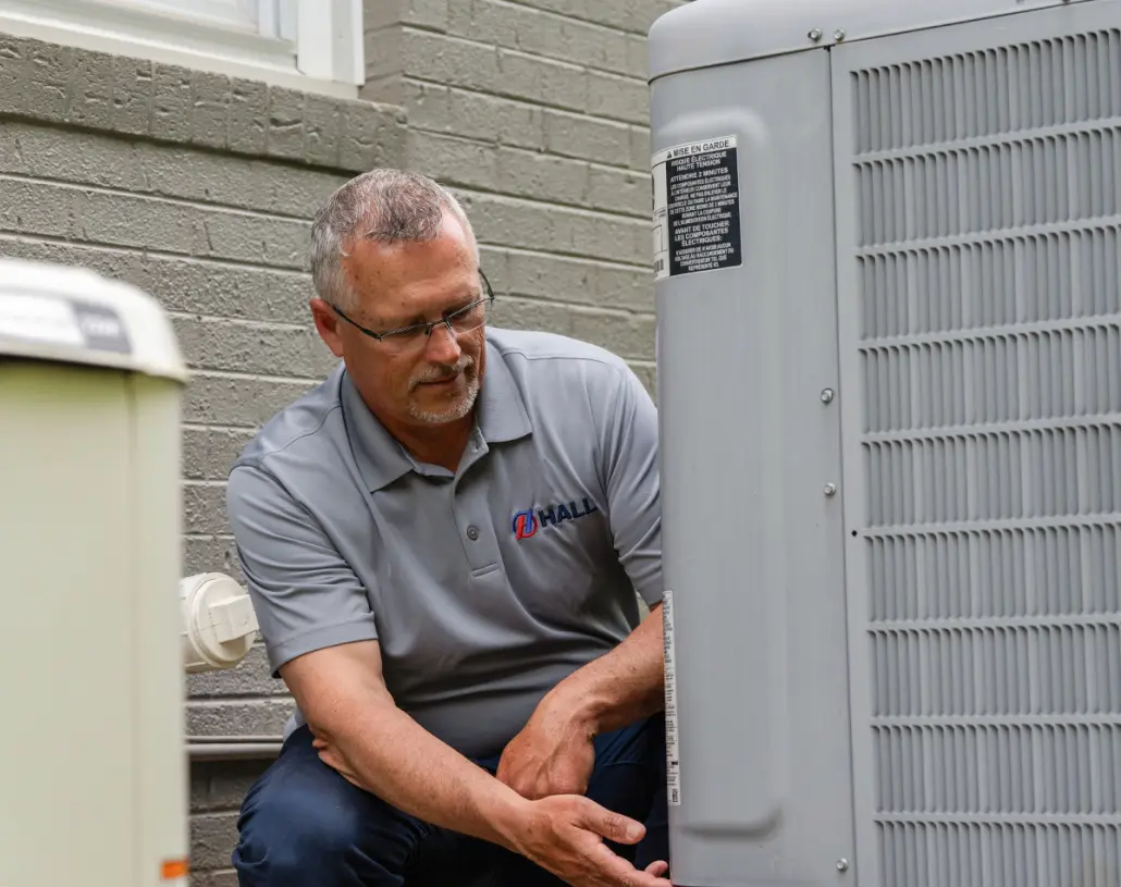 Hall HVAC technician working on an outdoor unit
