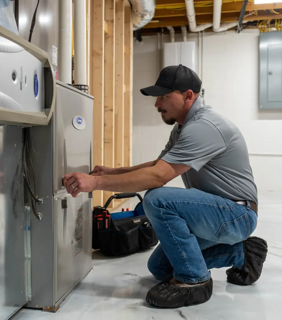 Hall HVAC technician working on an indoor furnace