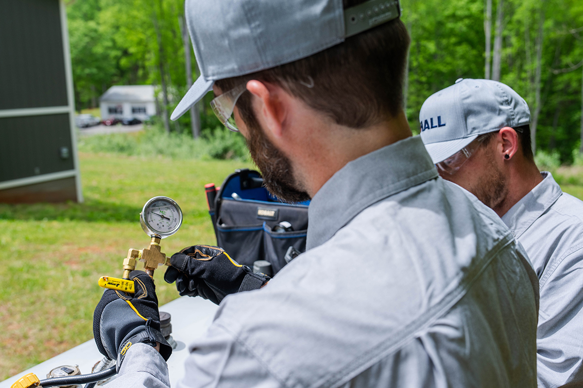 Hall technician checking a pressure gauge on a propane tank