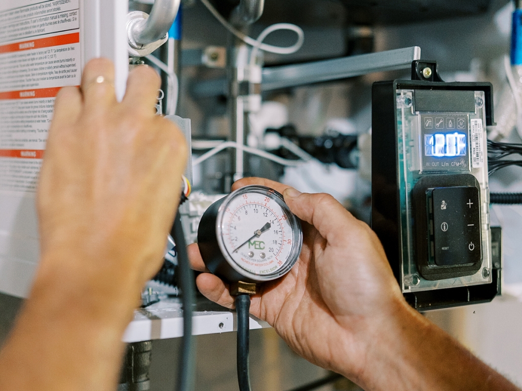 Hall technician performing maintenance on a tankless water heater