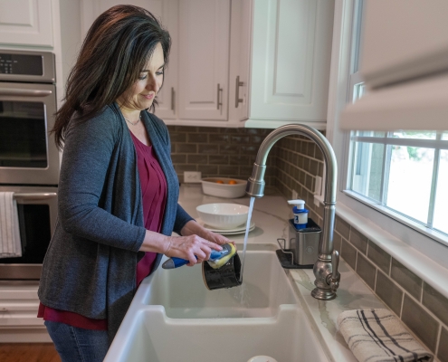 Person washing dishes in a kitchen sink