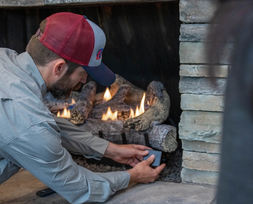 Hall technician servicing a gas log fireplace