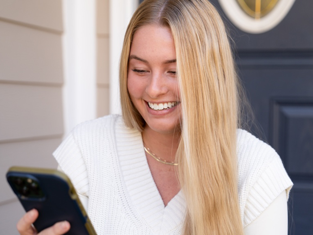 Hall Propane customer smiling while looking at her phone