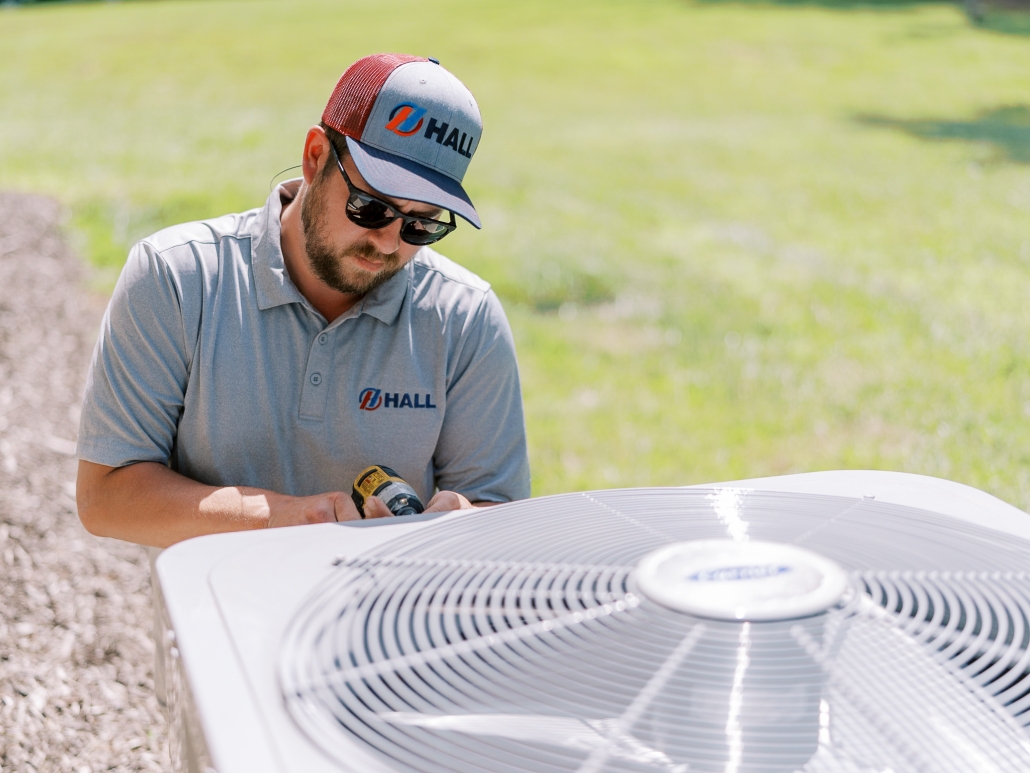 Hall technician performing air conditioner repairs.