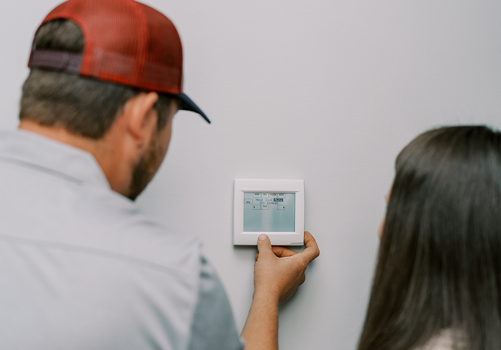 Hall technician helping customer with thermostat settings