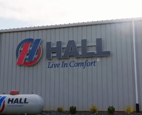 Hall "Live In Comfort" sign on the side of a steel building.